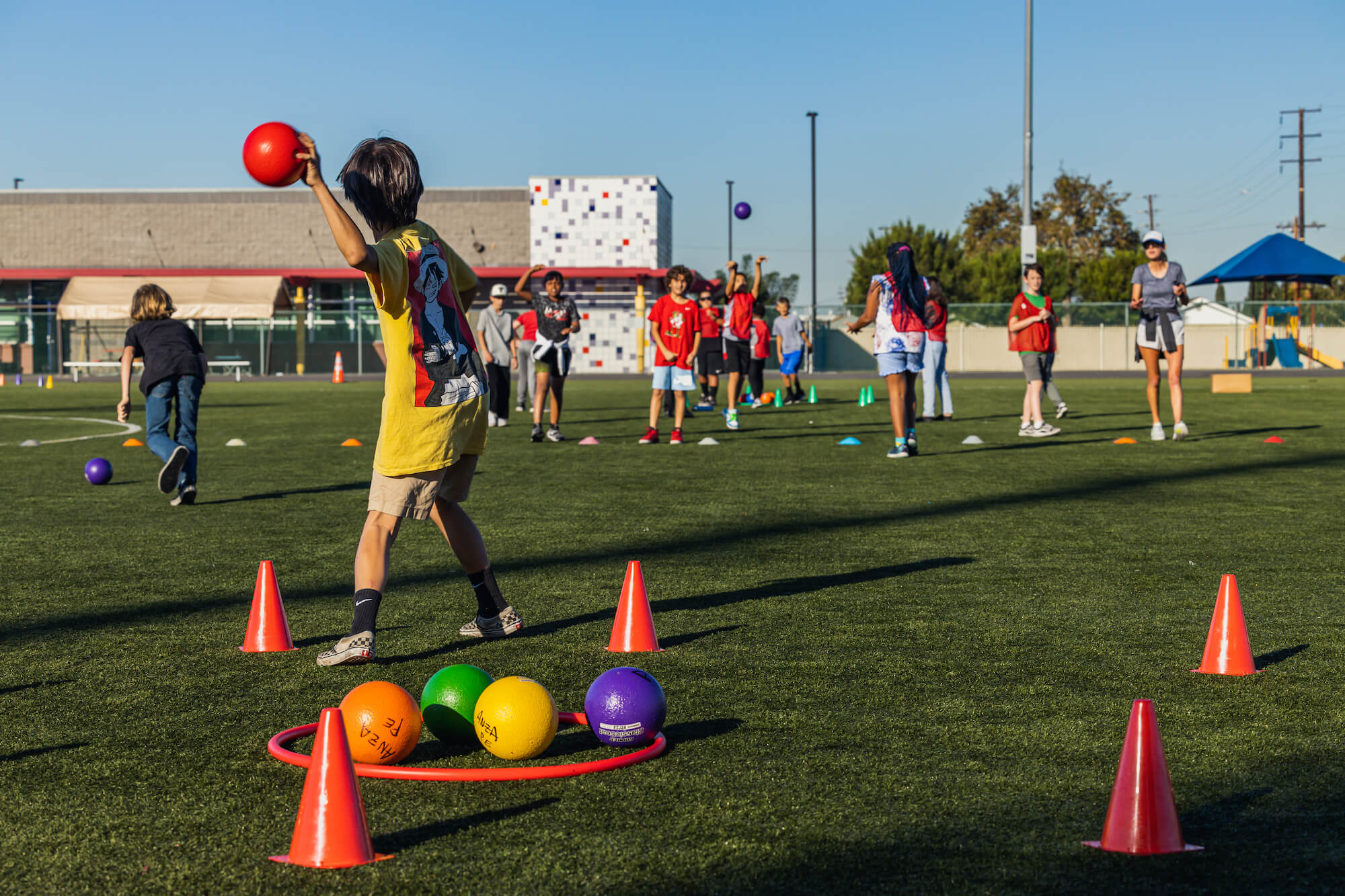Students play a dodgeball-type game on a school field.
